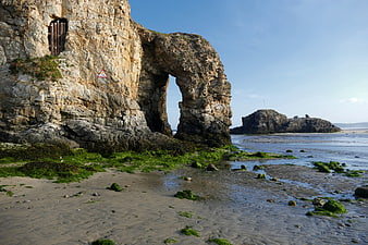 Natural Rock Arch on Sandy Beach at Low Tide