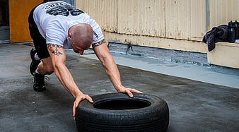 Muscular Man Performing Tire Push Workout Outdoors