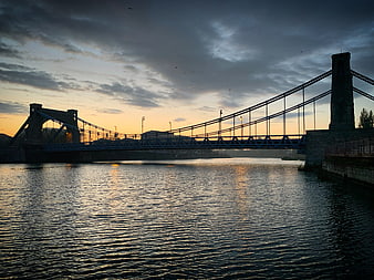 Suspension Bridge Silhouette Over River at Dusk