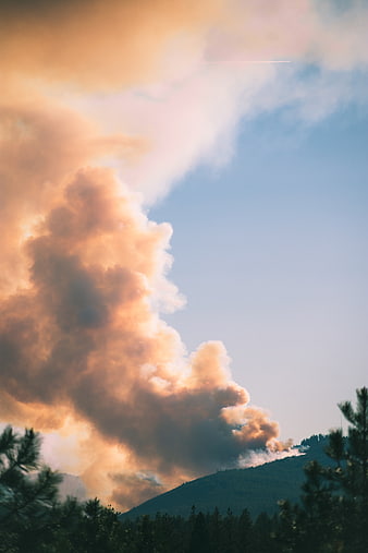 Massive smoke plume rising from forest fire over mountain ridge