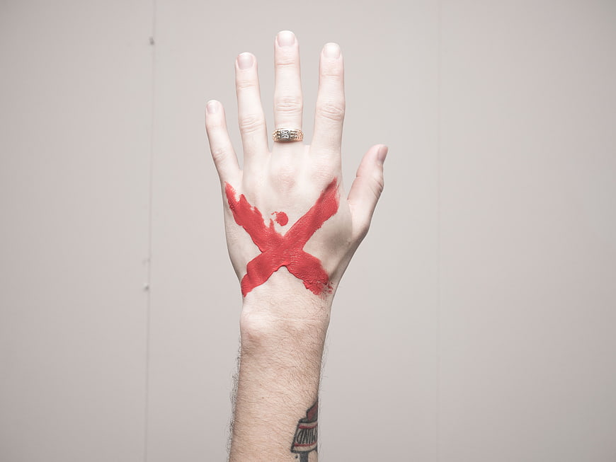 Hand with Red Paint X Mark and Gold Ring