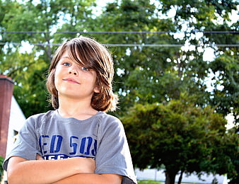 Portrait of a young boy with arms crossed outdoors