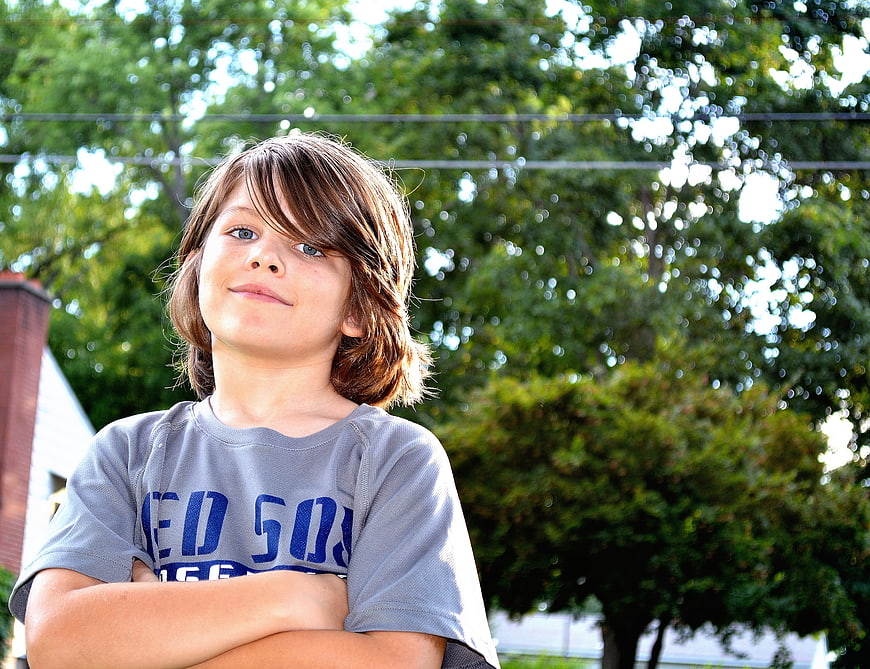 Portrait of a young boy with arms crossed outdoors