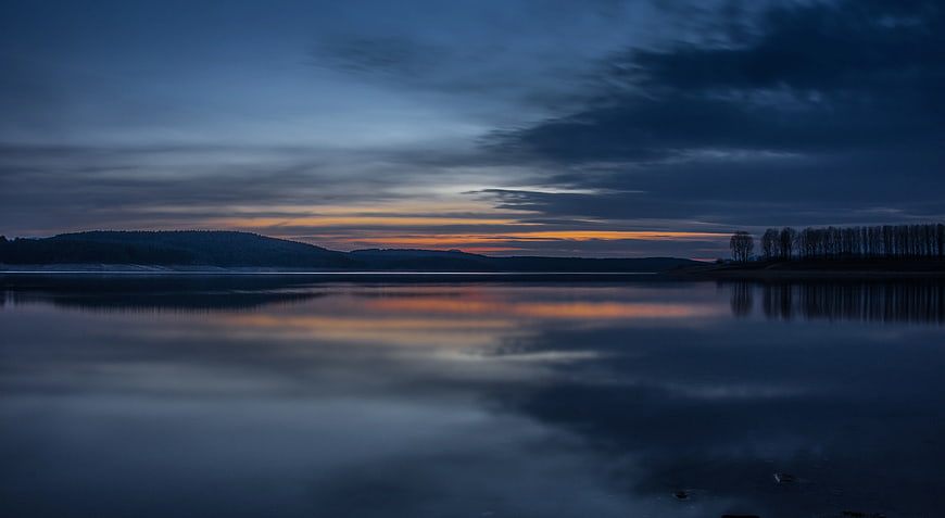 Serene Lake Sunset with Orange Horizon and Blue Sky Reflection