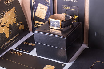 Luxury gold watch on black box with branding materials