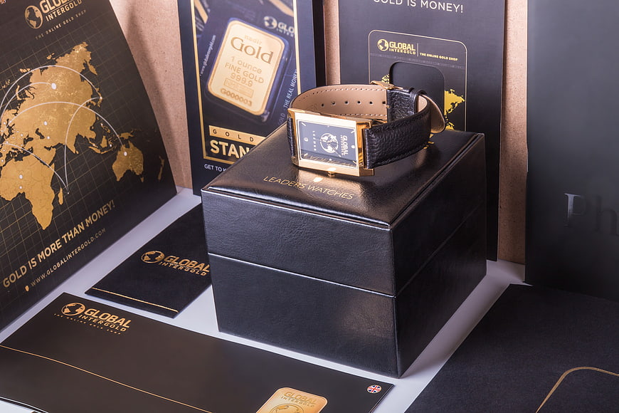 Luxury gold watch on black box with branding materials
