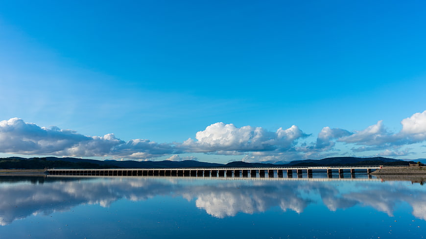 Serene Lake Dam with Cloud Reflections and Blue Sky