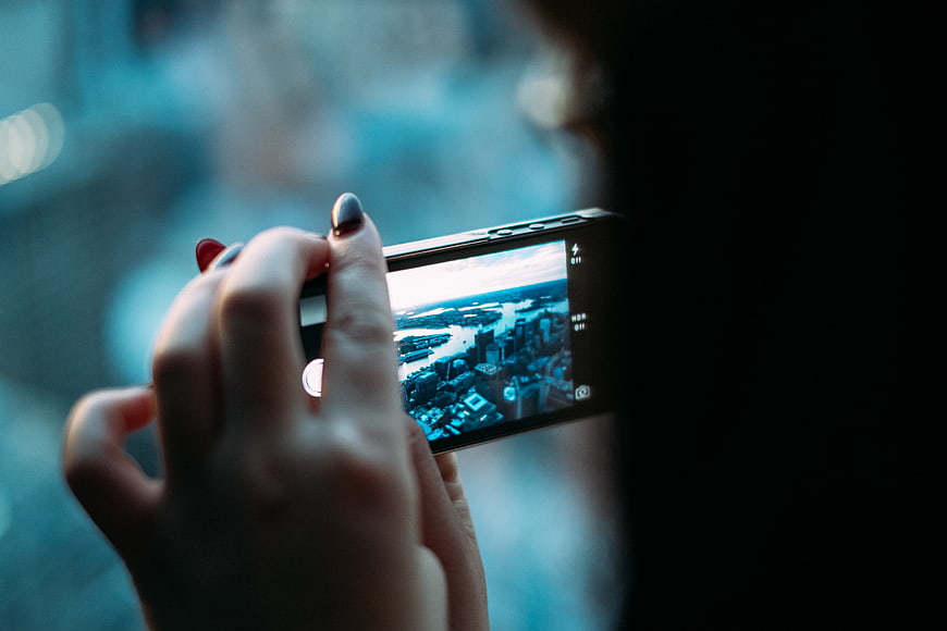Woman taking photo of city skyline with smartphone