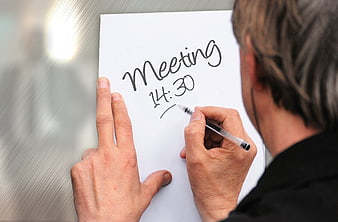 Man writing meeting time on whiteboard