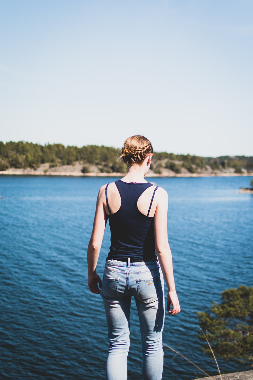 Woman Looking Out at Blue Lake on Sunny Summer Day