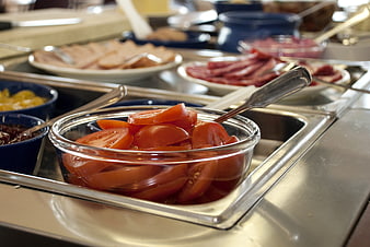 Fresh sliced tomatoes in glass bowl on buffet line