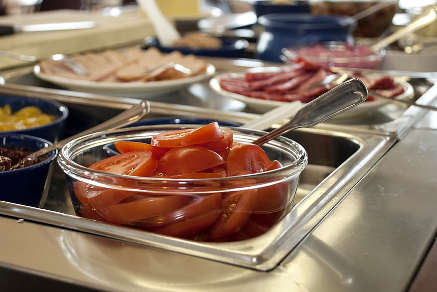 Fresh sliced tomatoes in glass bowl on buffet line