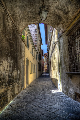 Narrow cobblestone alley in Tuscany, Italy with archway
