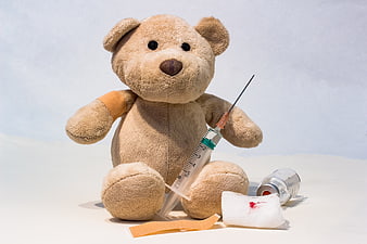 Teddy Bear with Syringe and Medical Supplies on White Background