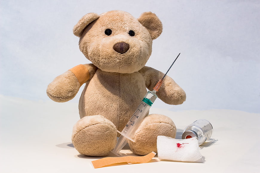 Teddy Bear with Syringe and Medical Supplies on White Background