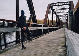 Runner stretching on wooden bridge railing autumn