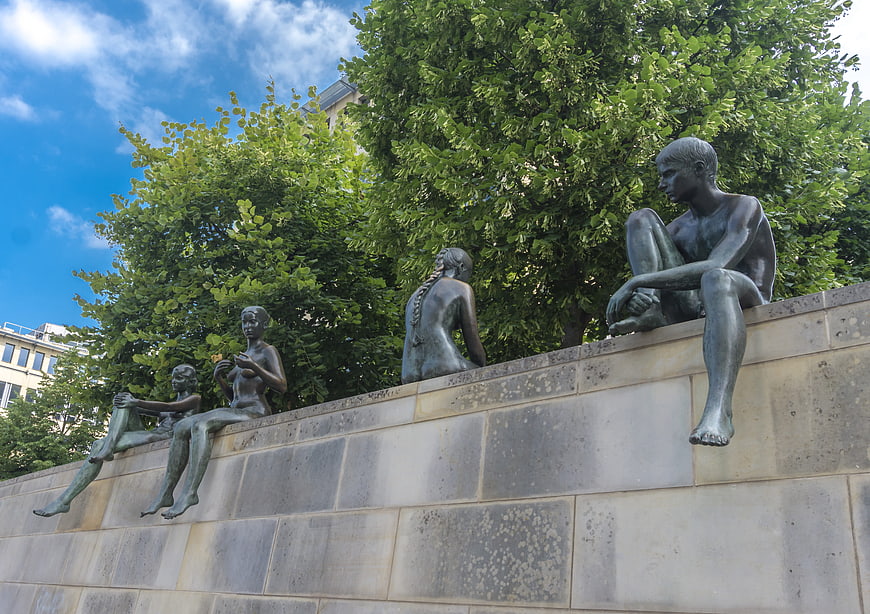 Bronze Sculptures of Children Sitting on Stone Wall in Berlin