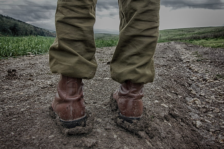 Close-up of military boots and trousers on a gravel path