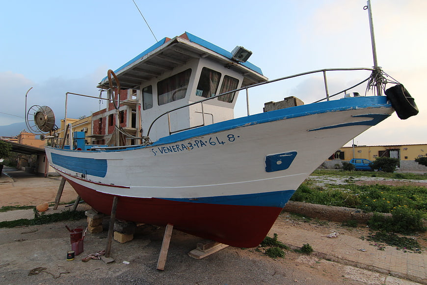 White and blue fishing boat on land in Sicily