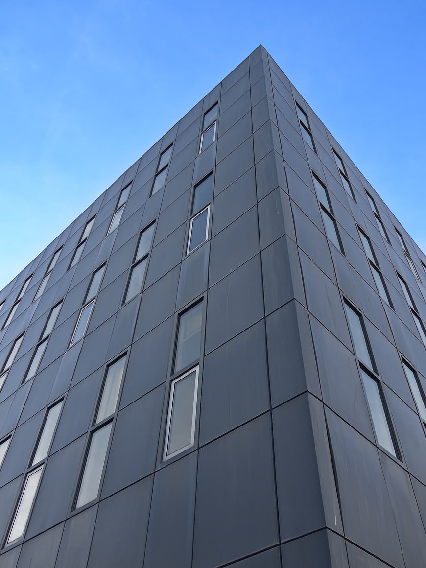 Modern Dark Gray Office Building Facade Against Blue Sky