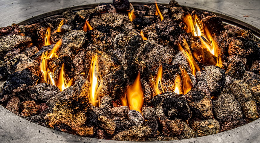 Close-up of burning charcoal and flames in a metal fire pit