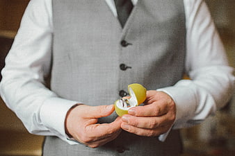 Groom holding wedding ring in yellow box