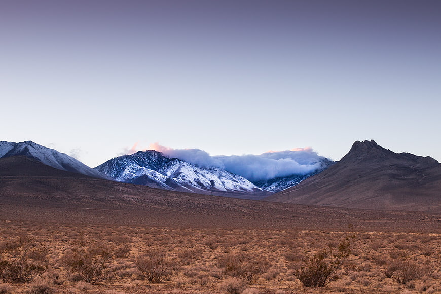 Snow-Capped Mountain Peak with Clouds in Desert Landscape