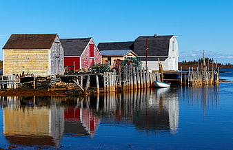 Colorful weathered fishing shacks on wooden stilts with water reflections