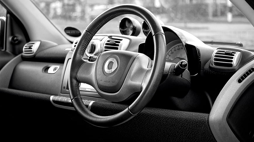 Black and white car interior with steering wheel and dashboard