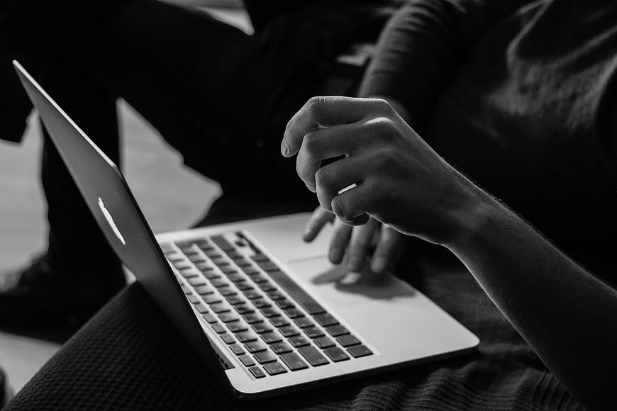Close-up of hands typing on a laptop in black and white