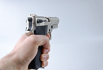 Hand Holding Silver Pistol Against White Background