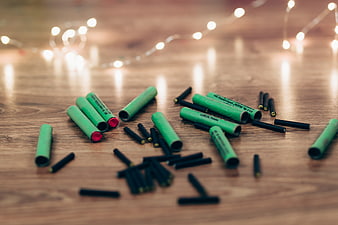 Green and black chalk pieces scattered on wooden table with bokeh lights