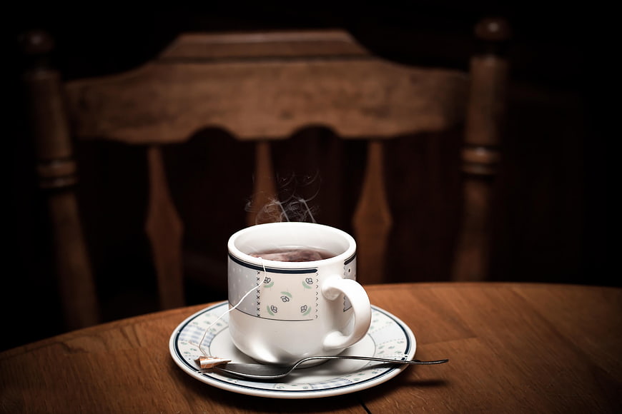 Steaming cup of hot tea on wooden table