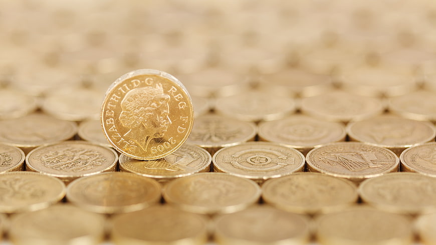 Close-up of British Pound Coins with One Standing Upright