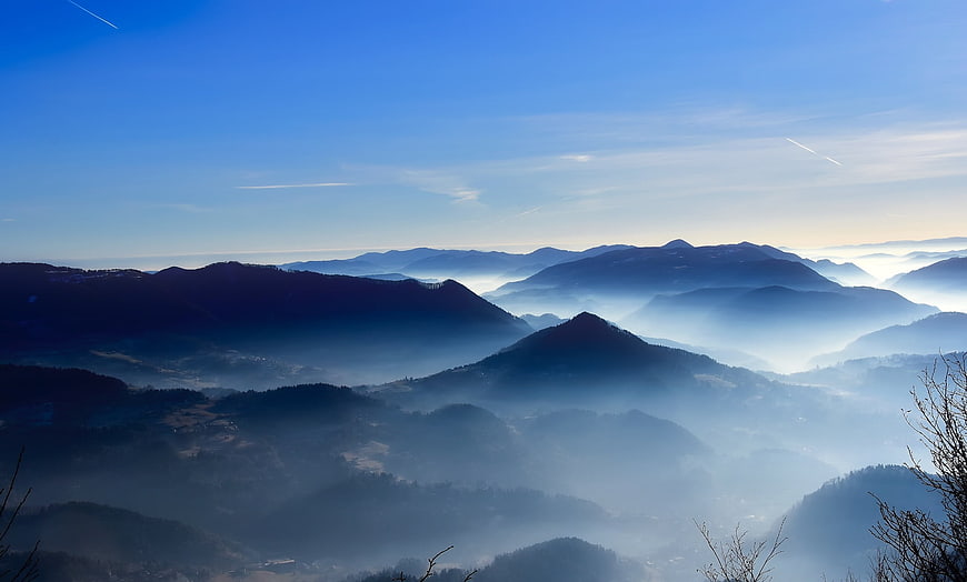 Misty mountain landscape at dawn with blue sky and fog in valley