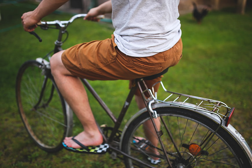 Man riding bicycle in shorts and flip-flops on grass