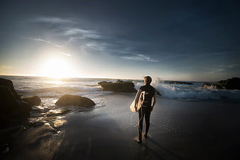 Surfer Walking on Beach at Sunset with Surfboard