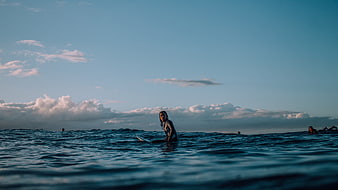 Surfer in Ocean with Blue Sky and Clouds