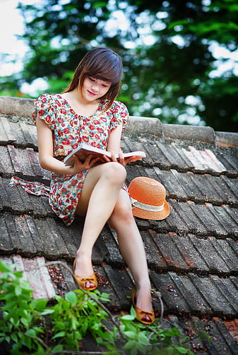 Young woman reading book on rustic tiled roof