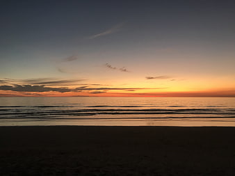 Serene Sunset Over Calm Ocean Waves on Sandy Beach