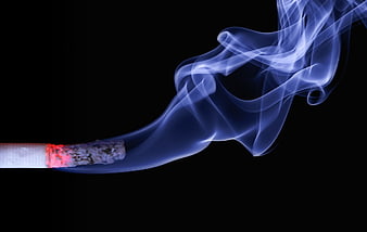 Close-up of burning cigarette with blue smoke on black background