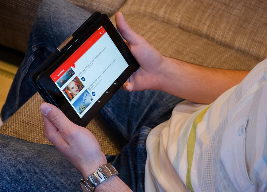 Person holding tablet with YouTube app on lap