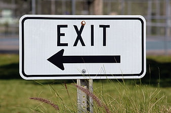 White Exit Sign with Left Arrow in Grass