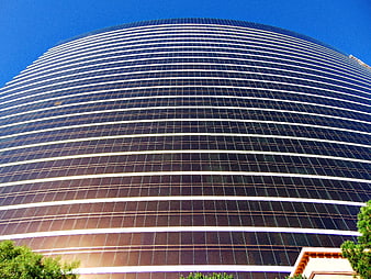 Low angle view of modern curved glass skyscraper facade