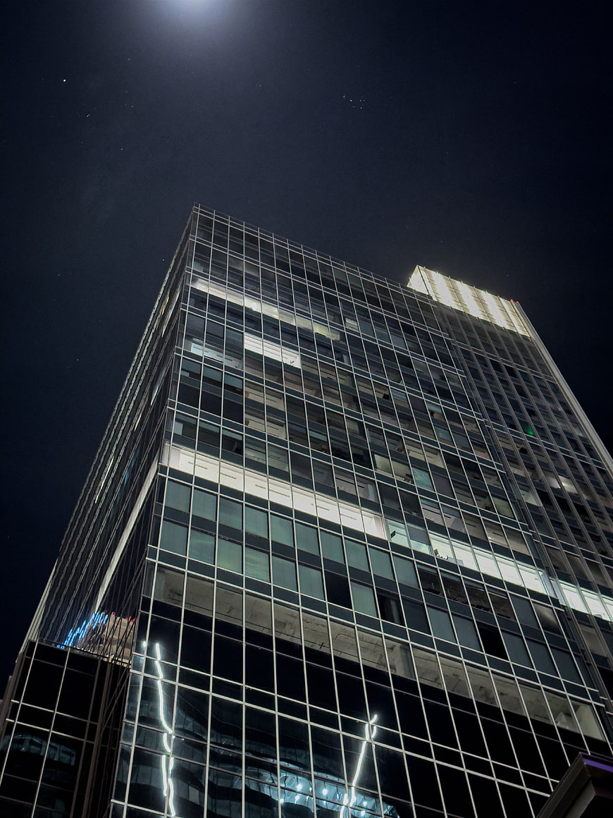 Low angle view of modern glass skyscraper at night