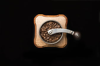 Top view of wooden manual coffee grinder with roasted beans