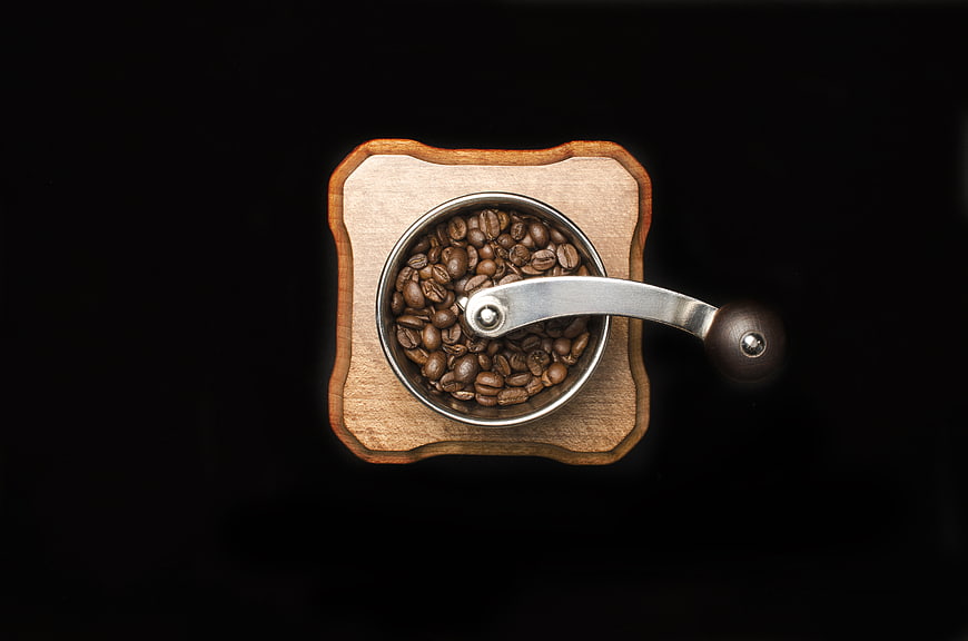 Top view of wooden manual coffee grinder with roasted beans