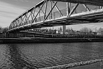 Black and white industrial truss bridge over a river