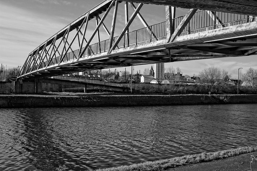 Black and white industrial truss bridge over a river