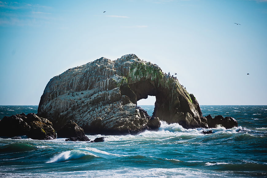 Dramatic Sea Arch Rock Formation with Birds and Waves